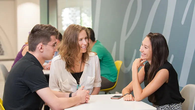 Three students chatting at a table