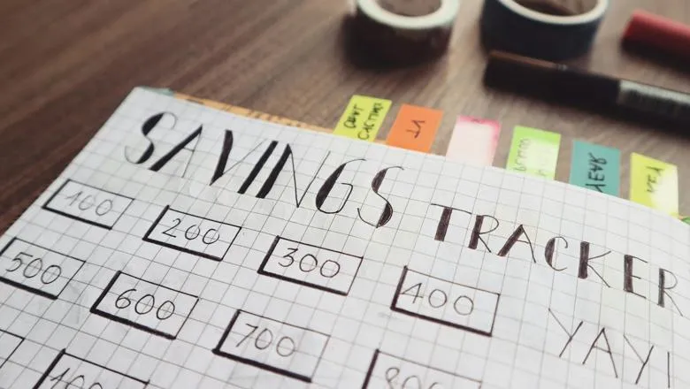 A handwritten savings tracker with colourful tabs