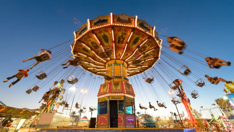 A carnival swing ride in action at a funfair during sunset.
