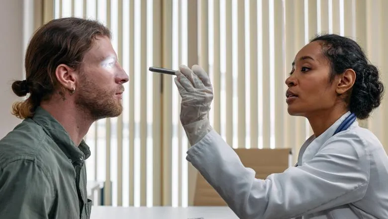 Female doctor examining male patient's right eye