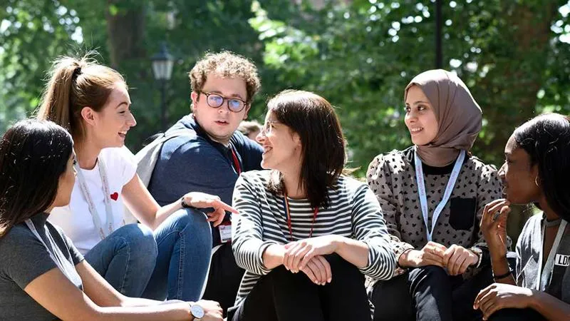 A photograph of a group of students on campus talking and smiling.