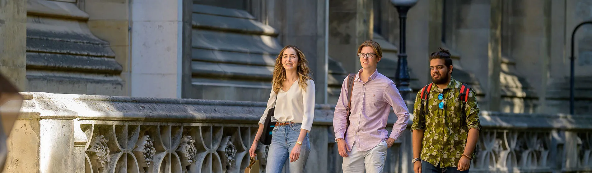 A photograph of three students walking by the Maughan Library.