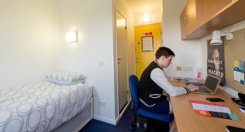 Student sat at desk in single en-suite bedroom