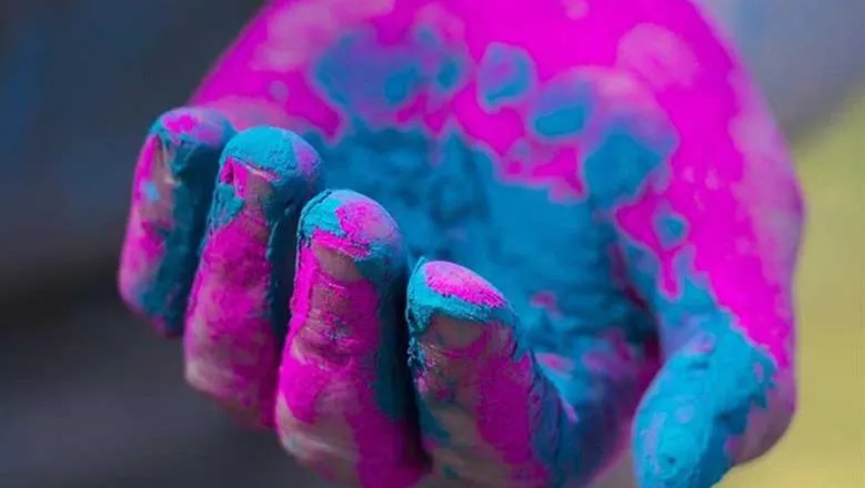 Open hand covered in pink and blue paint