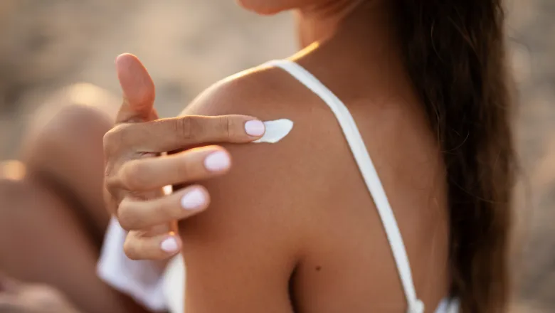 Woman applying sunscreen on her shoulder. Adobe Stock