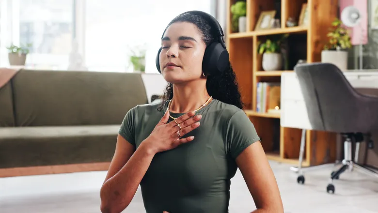 Young woman wearing headphones, doing breathing exercises while listening to music