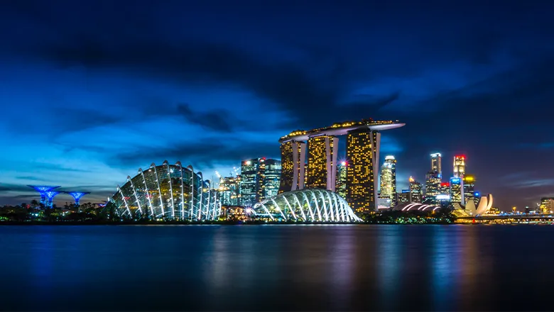 The Singapore skyline at dusk, with the lights of the city glittering over the coastline.
