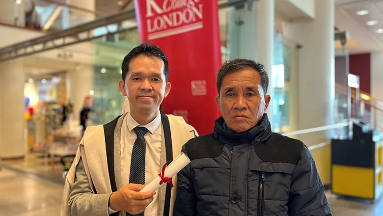 Sythan Prou is pictured at his graduation with his father. He is holding his degree, and is wearing his graduation gown.