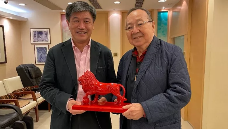 An image of Dr Bertrand Leung being handed a small statue of Reggie the lion, The King's College London mascot, by William Kwan FKC.