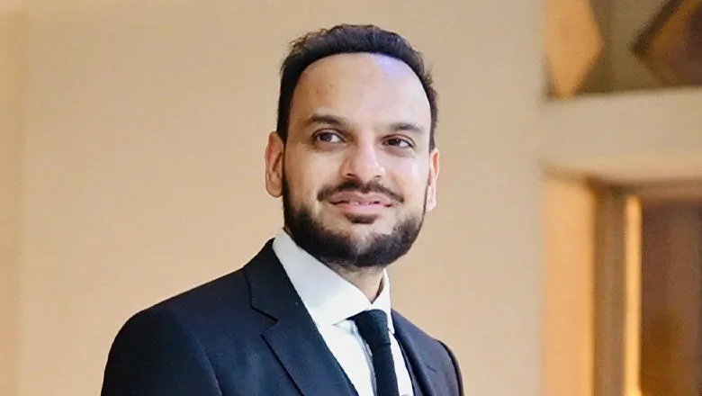 Headshot of Nouman Syed smiling warmly, dressed in a suit and tie. 