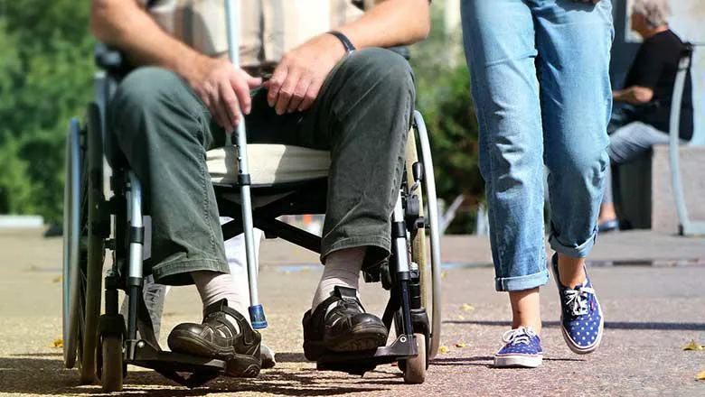 A man sitting in a wheelchair with a woman walking beside him