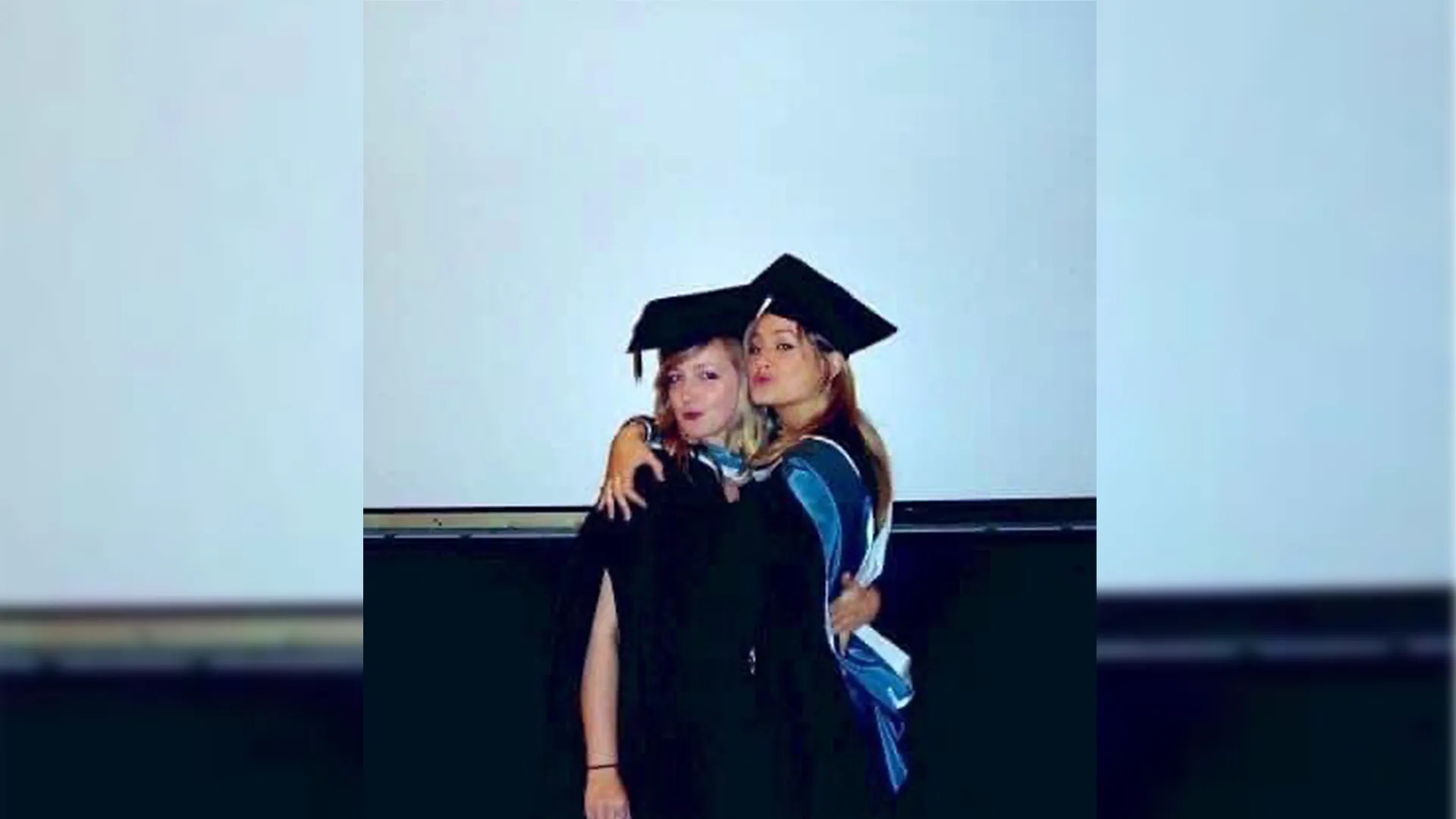 Kate Marlais and Alex Young are hugging each other, wearing their graduation gowns