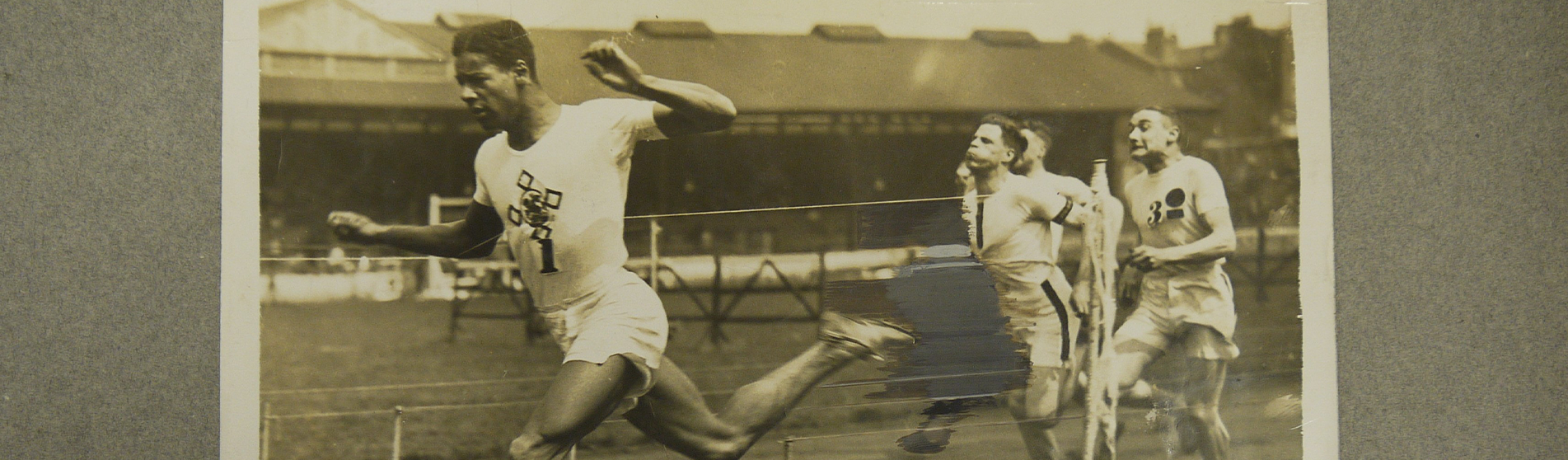 A black and white photograph of four men competing in the 100 yards race.