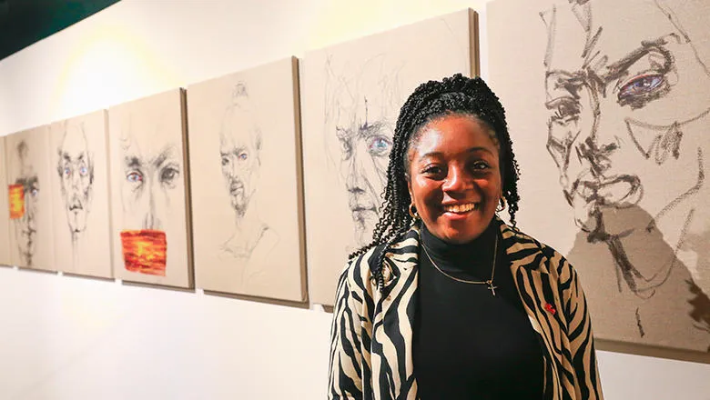 Onyinye smiles in front on paintings
