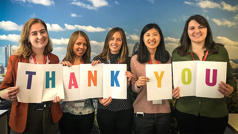 King's alumni office staff members pose with cards saying 'thank you'.