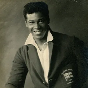 Jack London, a man of Afro-Caribbean heritage, smiles at the camera, wearing a white shirt and blazer.