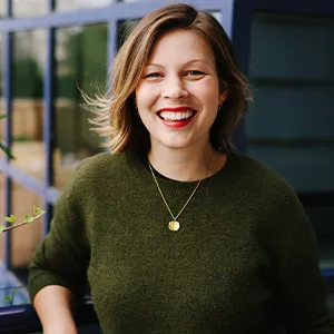 Julia wearing a gold necklace and green jumper