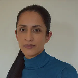 Sabrina in profile, wearing a blue turtle neck in front of a grey background