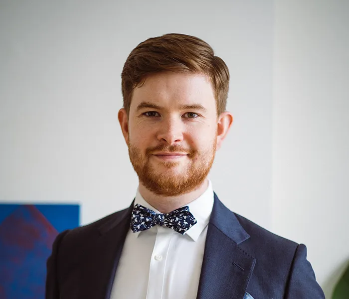 An image of Patrick McCrae, CEO of Artiq and King's College London graduate. He is wearing a blue suit and bowtie.