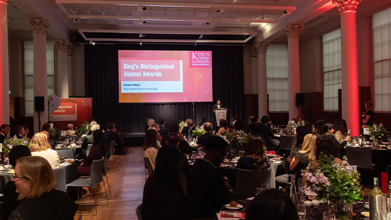 Alumni and staff gather in the Hall at King's for 2022's Distinguished Alumni Awards event - tables are adorned with flowers, and Principal Shitij Kapur stands on the stage speaking