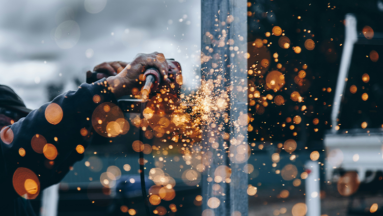 Sparks fly as a man uses a tool on a construction site.