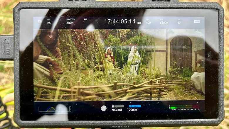 An image on a camera of two actresses standing in a garden, wearing medieval dresses.