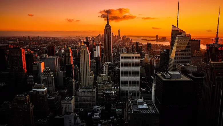 The sun sets over New York, with the Empire State Building occupying the centre of the image.