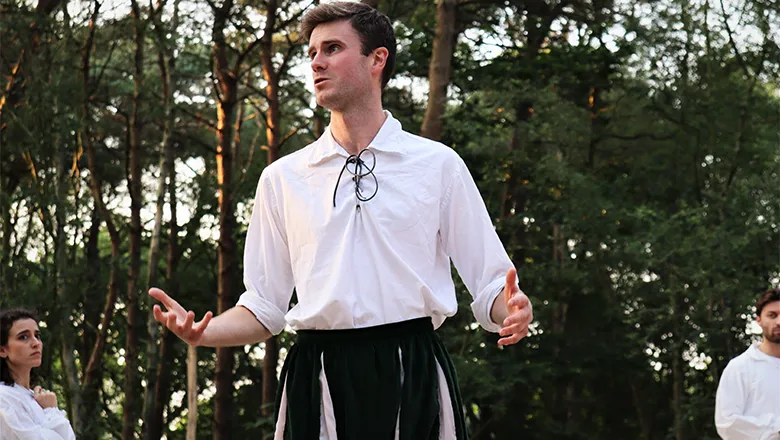 Joe, a young man dressed in an Elizabethan costume, performs on stage