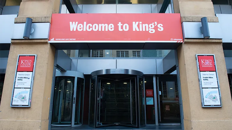 A red sign with 'welcome to King's' written on it above the entrance to a campus building