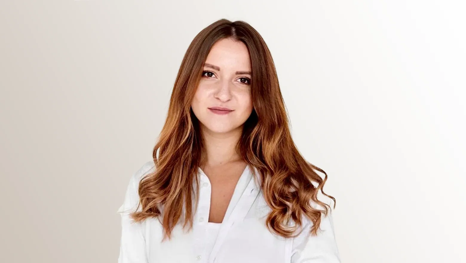 Valeriya Grebenkova is standing in front of a mushroom grey background, and is wearing a white shirt
