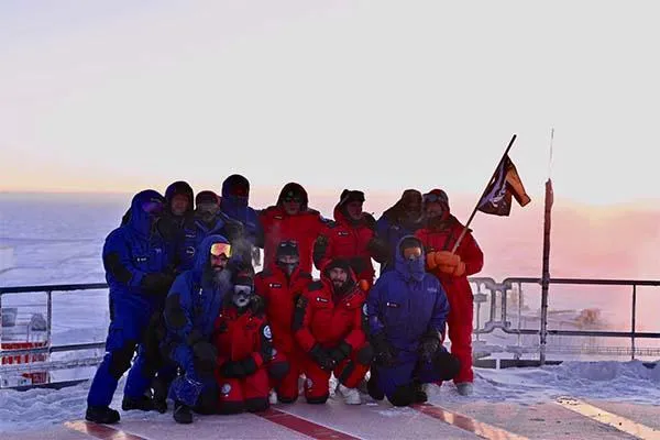 Nina and crew smiling warmly, as they stand together on the roof of the Concordia Station.  