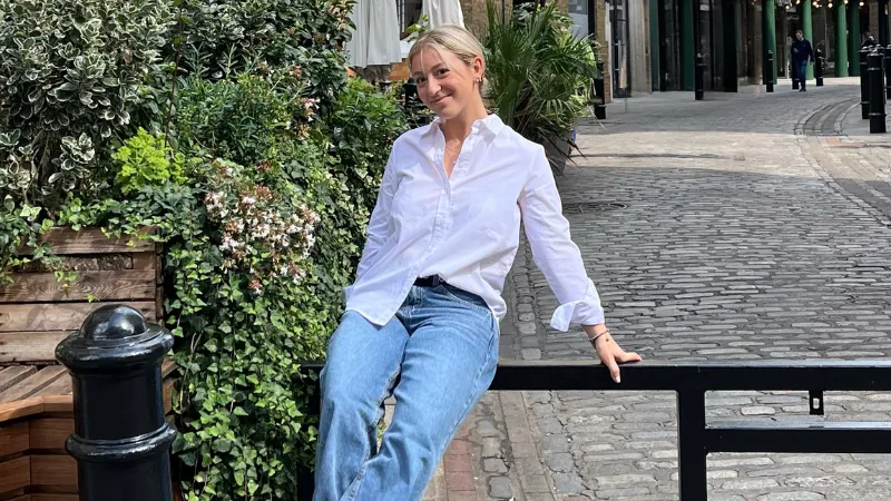 Ari smiles and sits on a gate