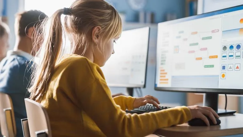 Schoolgirl learns computer science at desktop computer