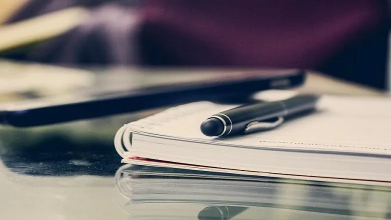 image of pen and notebook on office table