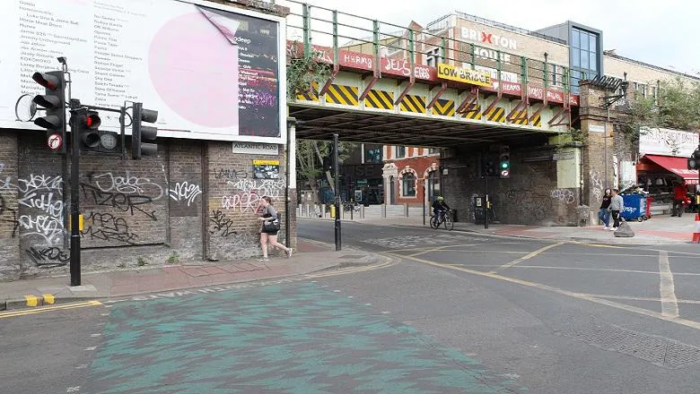 image of crossroads and bridge in brixton with person jogging on pavement
