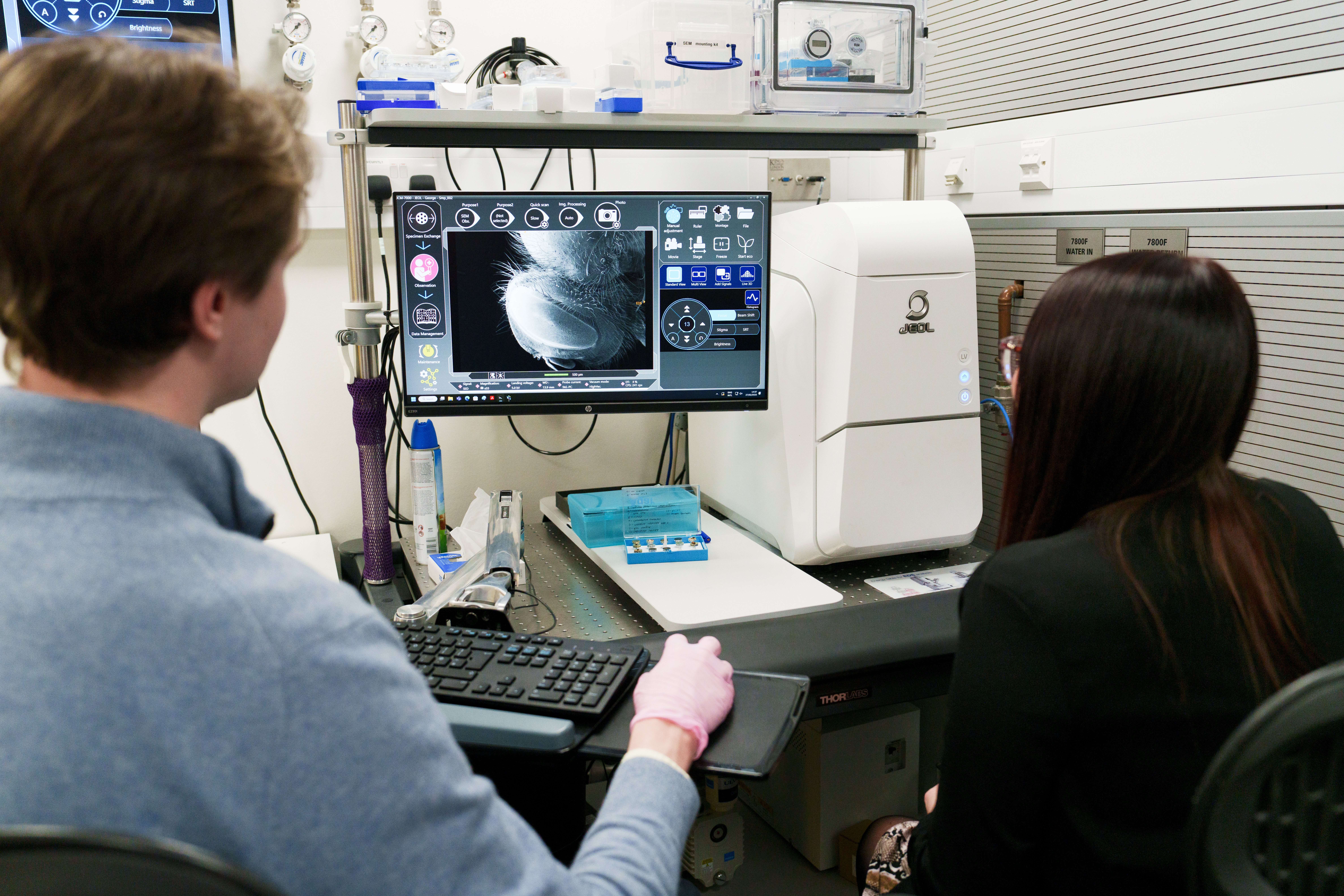 Two people looking at a microscope screen