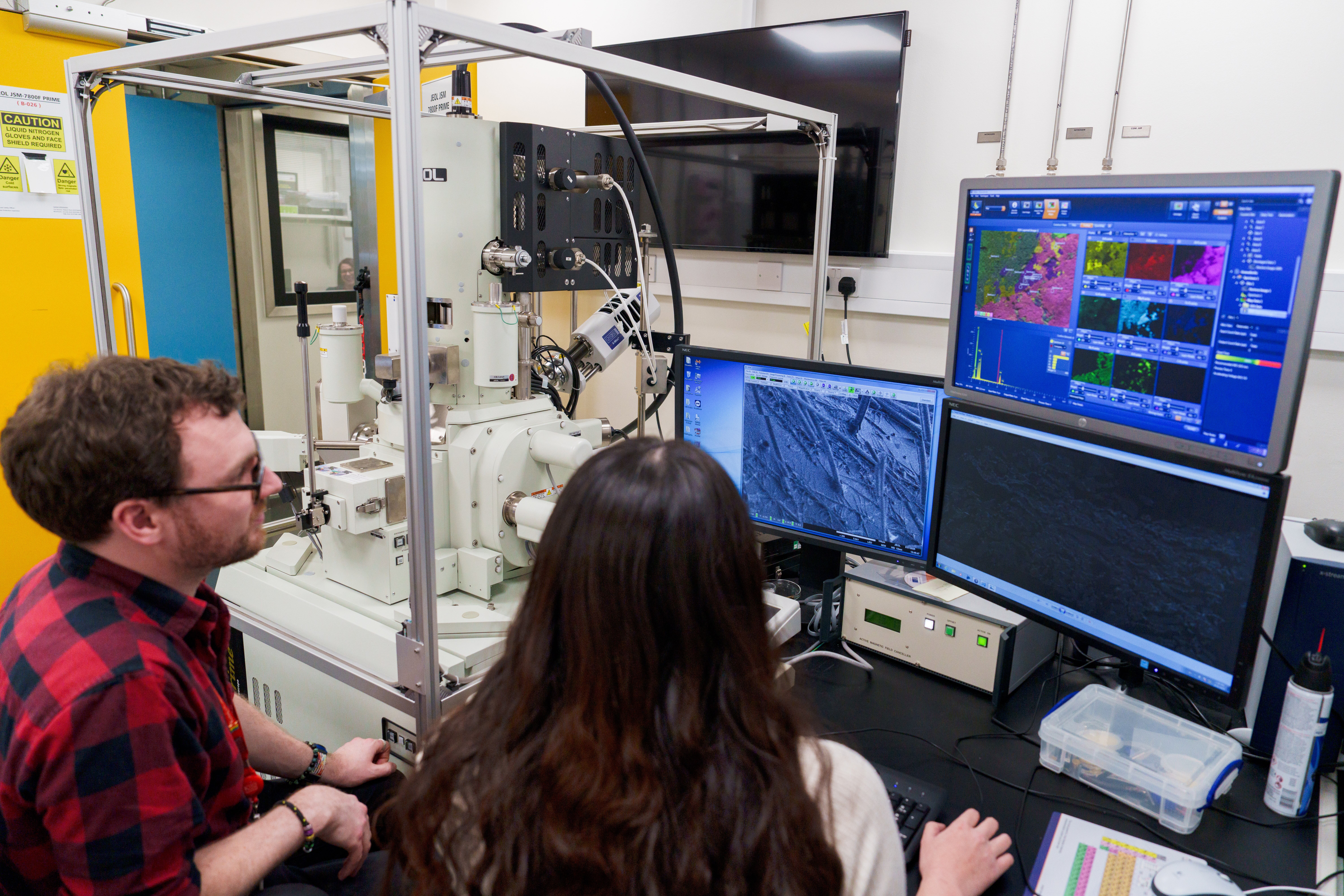 Two people looking at a microscope screen