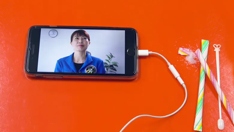 A iPhone playing a video on a orange surface with some sweets next to the iPhone