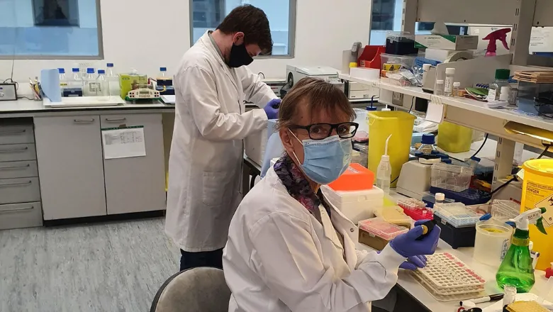 two people in a scientific laboratory wearing masks