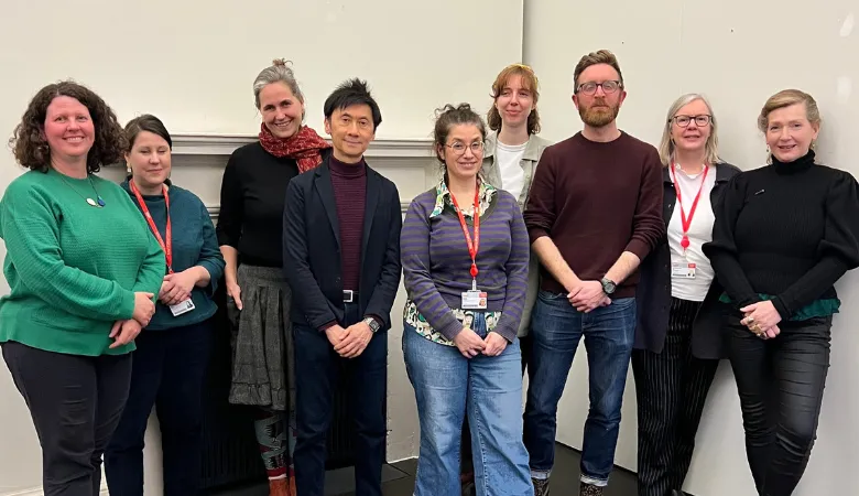 9 artists and academics standing together and smiling at King's Artists induction meeting