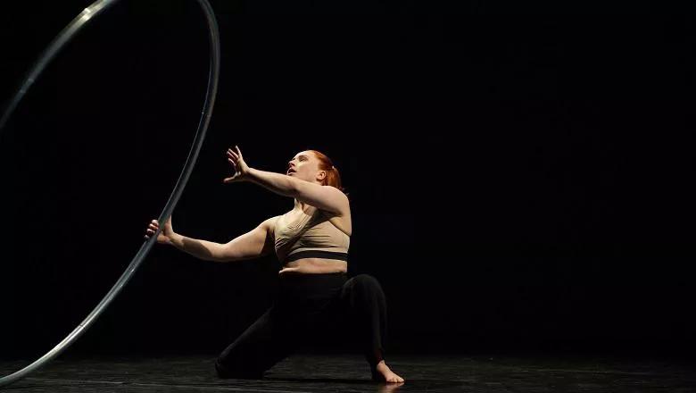 woman dancer with a large hoop performing on stage at the world cities culture forum with a black background