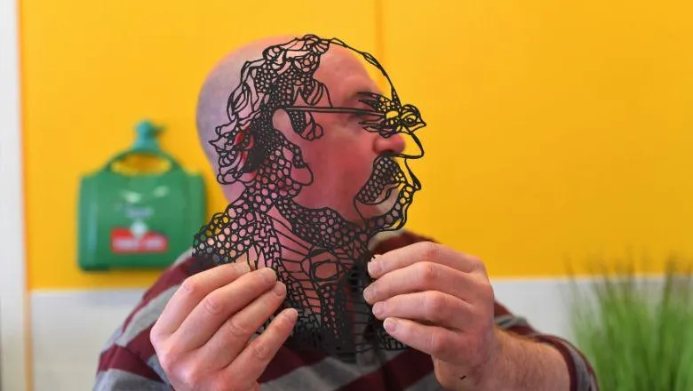 Image of man with a laser-cut artwork in front of his face