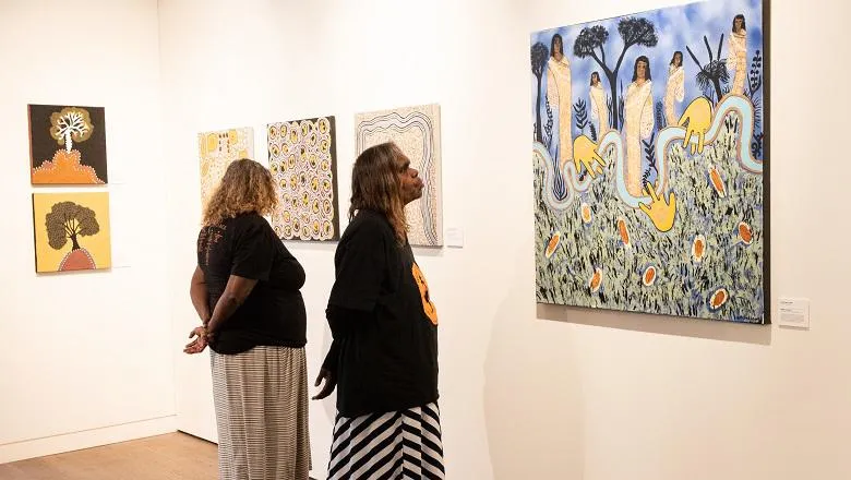 Two Ngangkari (traditional healers) look at paintings in The Art of Healing: Australian Indigenous Bush Medicine exhibitionibition