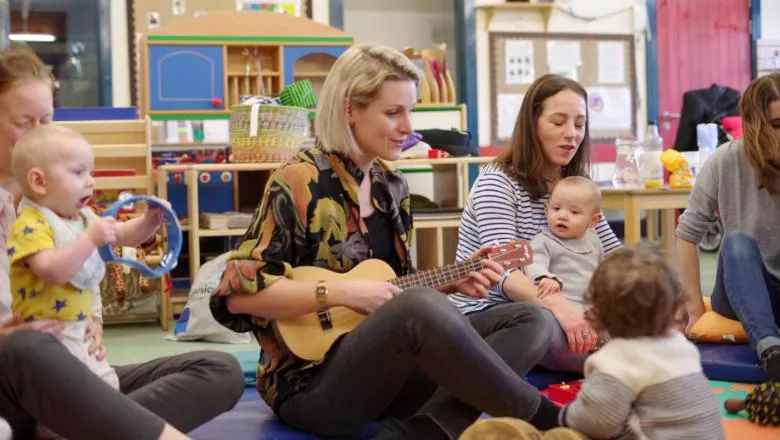A room with mothers and their babies singing together 