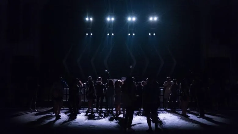 People standing on a dark stage with lights above