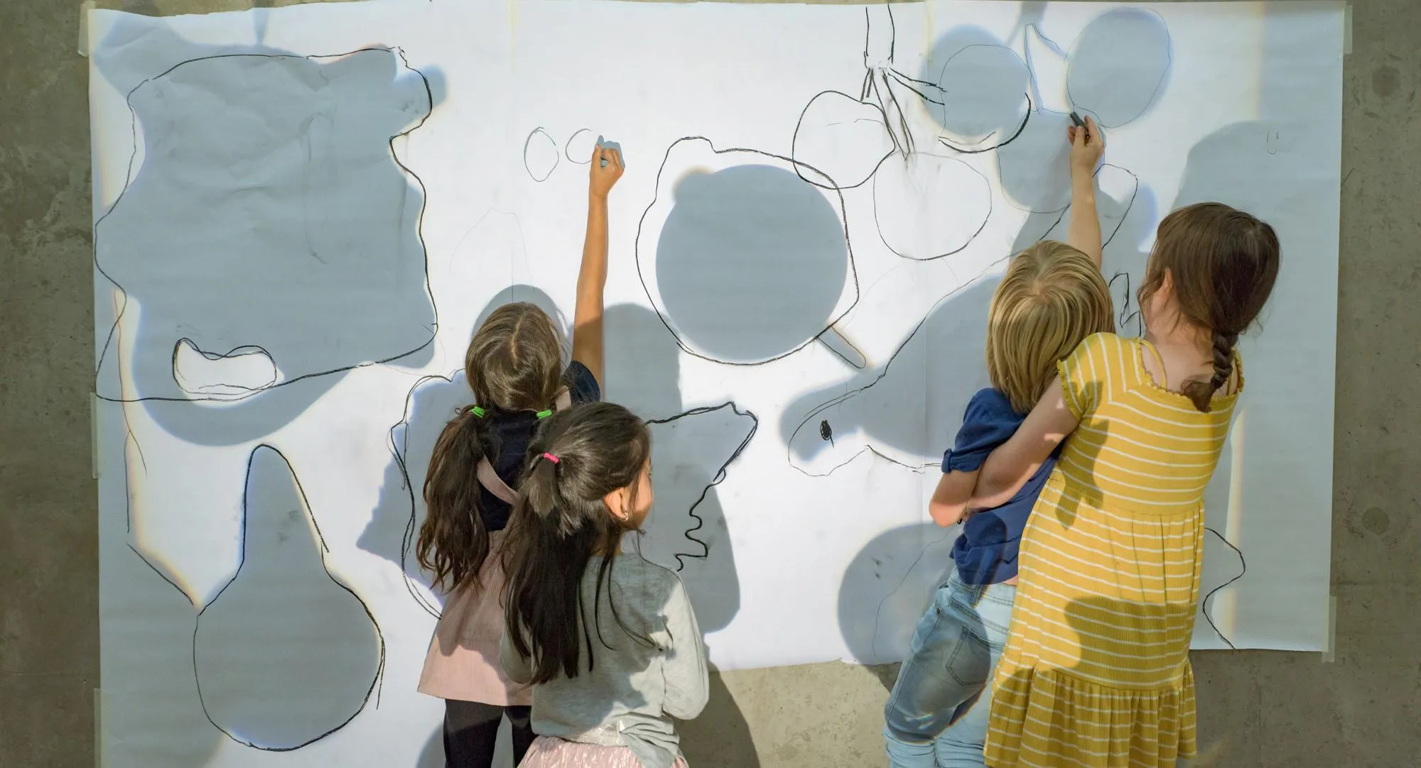 Children drawing on a large-scale canvas