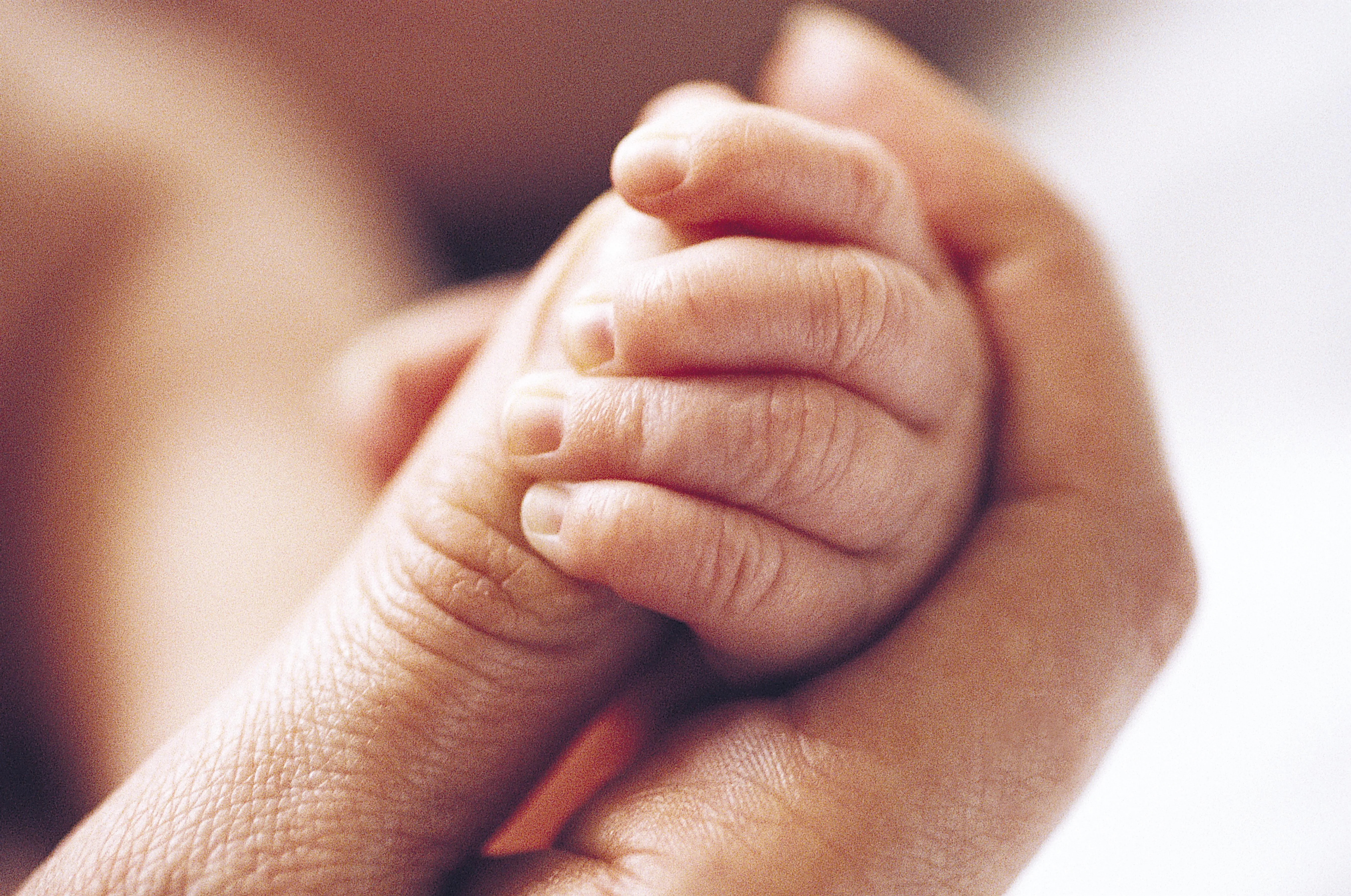 Baby holding parent's thumb