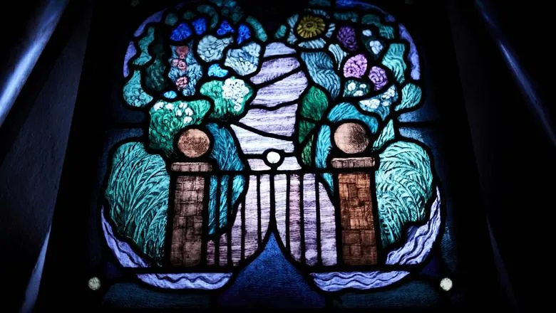 Stained glass window panel featuring garden gate and garden path with foliage on either side