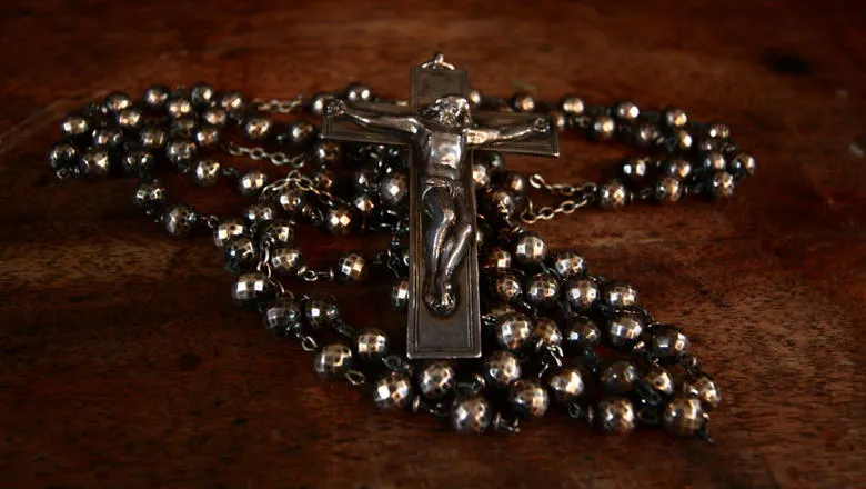 Pewter coloured Rosary on a wooden background