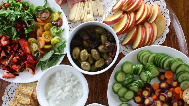 Sliced and chopped fruit and salad vegetables with cheese, olives, crackers and creamy dip